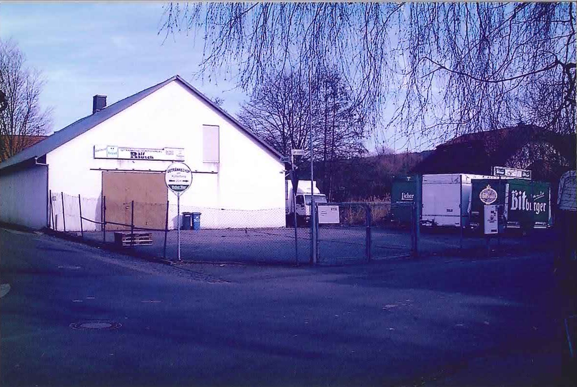 Außenansicht der alten Lagerhalle in der Karlstraße mit Firmenschild und Lieferfahrzeugen auf dem Hof.
