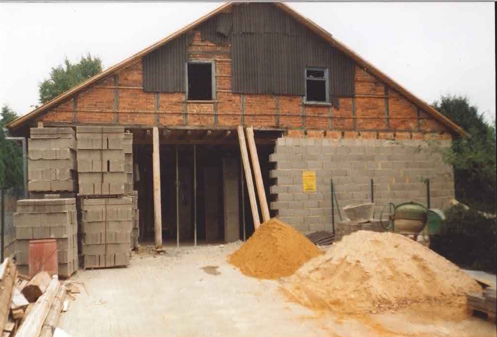 Bau der alten Lagerhalle in der Karlstraße: Rohbau mit Betonsteinen, Holzstützen und Materialhaufen auf der Baustelle.
