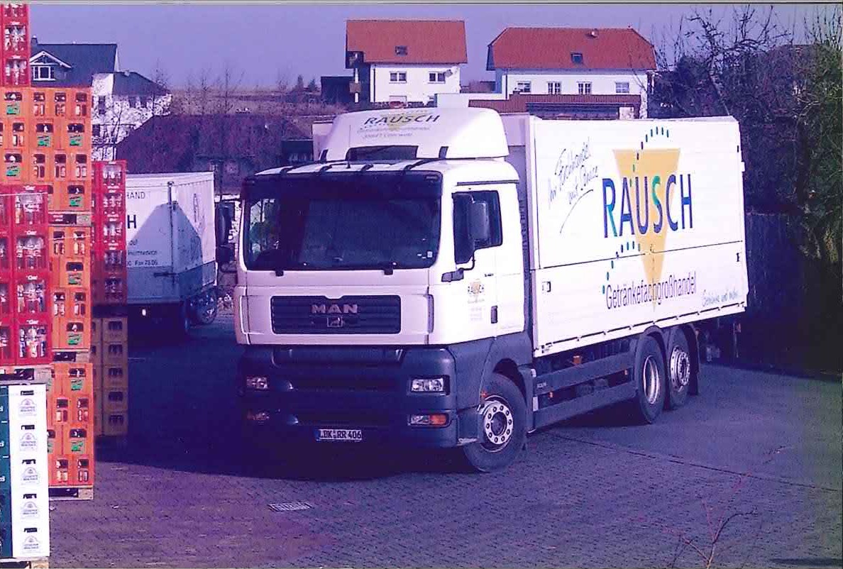 Rausch Getränke-LKW auf dem Hof, daneben gestapelte Getränkekisten – Lieferung und Logistik des Getränkefachgroßhandels.